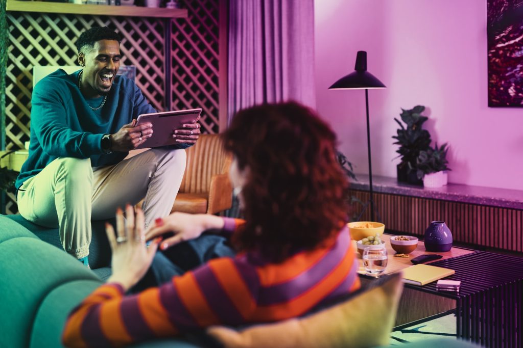 a woman sitting on a couch looking at a man using a laptop